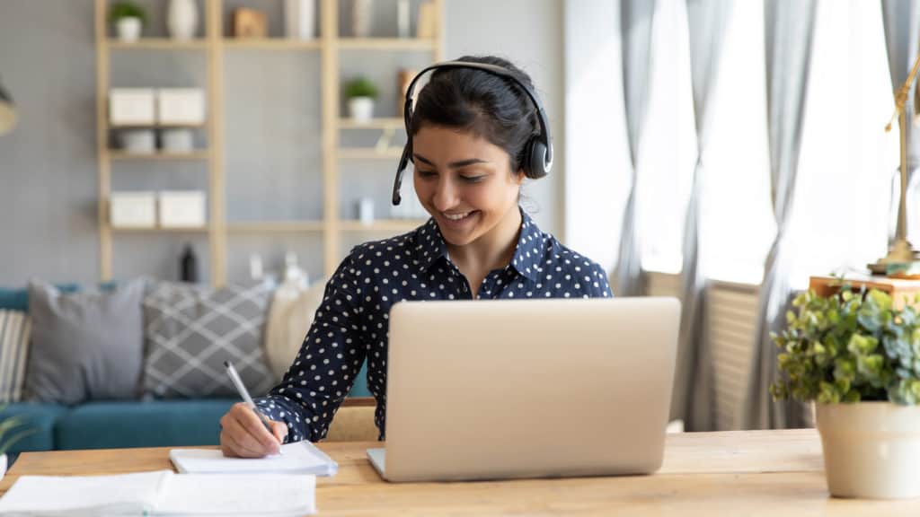 A female employee in a virtual workshop seminar using her laptop.