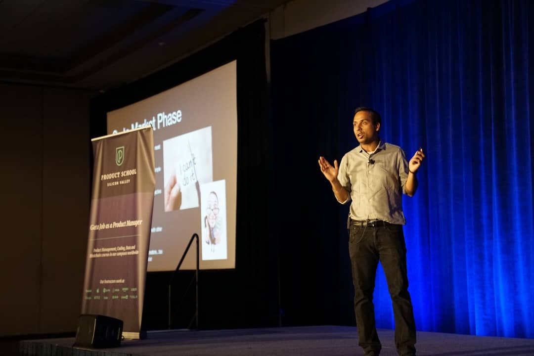 man standing in stage beside blue curtain - ai transformation kickoff