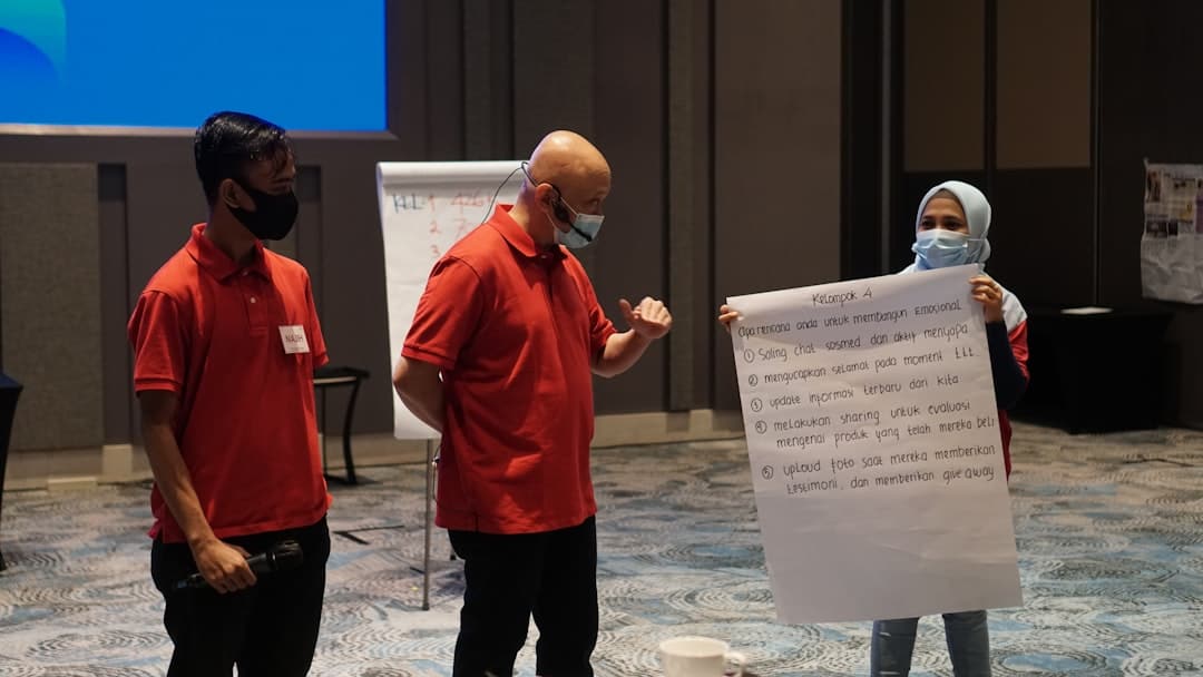 man in red polo shirt holding white printer paper - iaf vs hlc facilitation