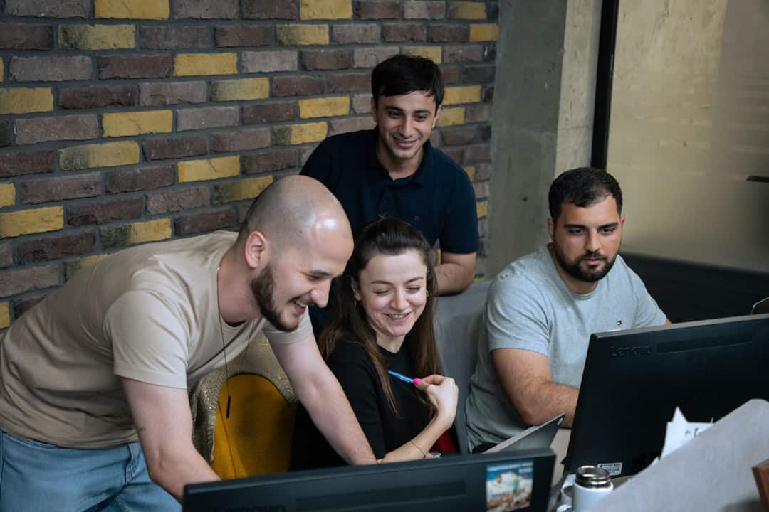 A group of people sitting around a laptop computer - AI fluency framework