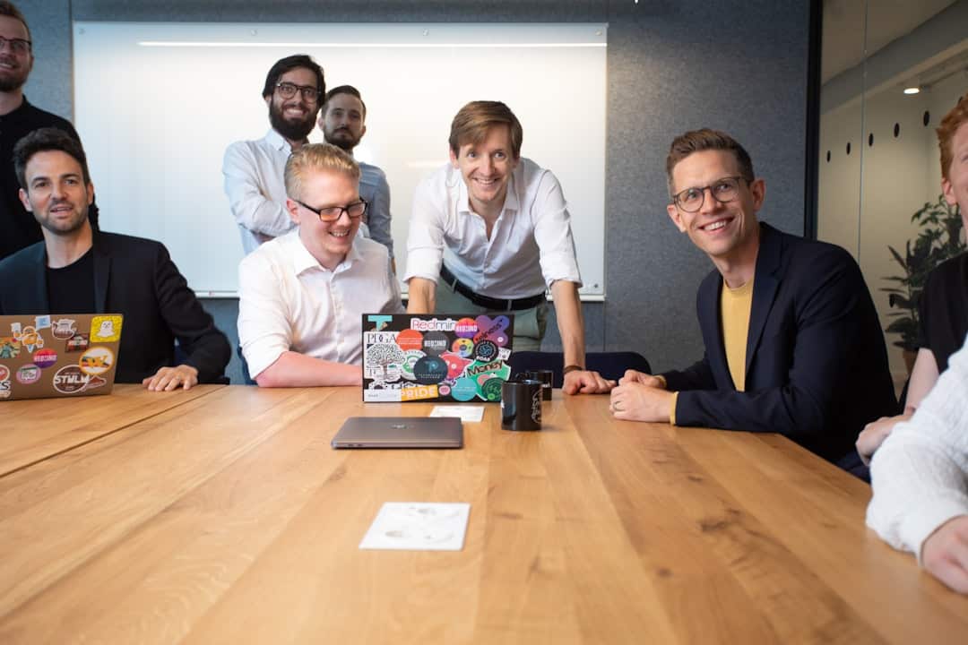 a group of people sitting around a wooden table - collaborative ai