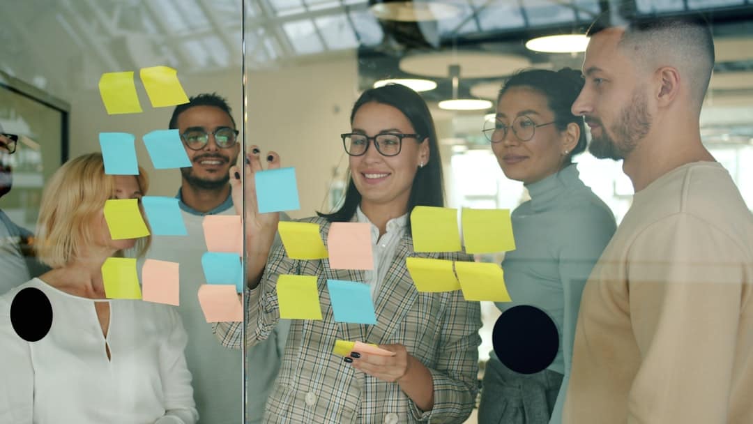 Team collaborating with sticky notes on glass wall - AI transformation strategy