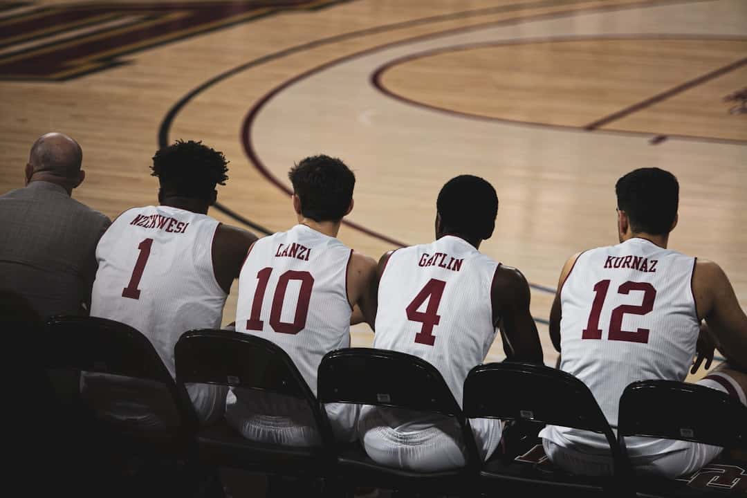 four basketball players sitting near another man in basketball court - AI teammates