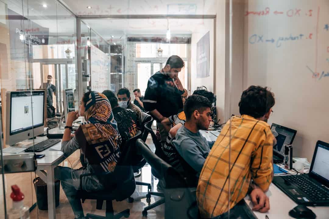 a group of people sitting at computers - applied agentic ai for organizational transformation