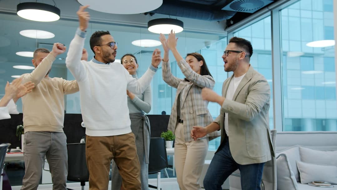A diverse group of colleagues celebrating success in an office. - ai transformation partner