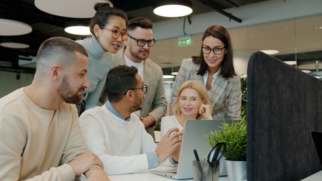 Diverse team collaborating around a laptop in office. - digital transformation with ai
